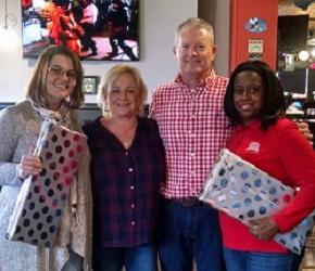 A cheerful group celebrating with wrapped gifts.