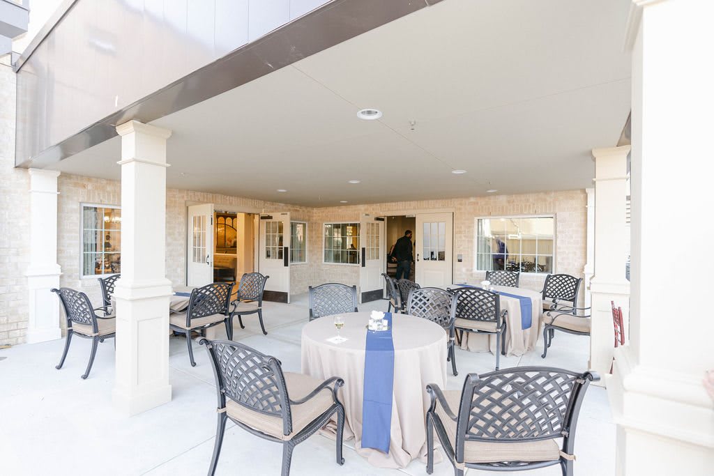 A covered patio area featuring several tables and chairs, providing a comfortable outdoor setting.