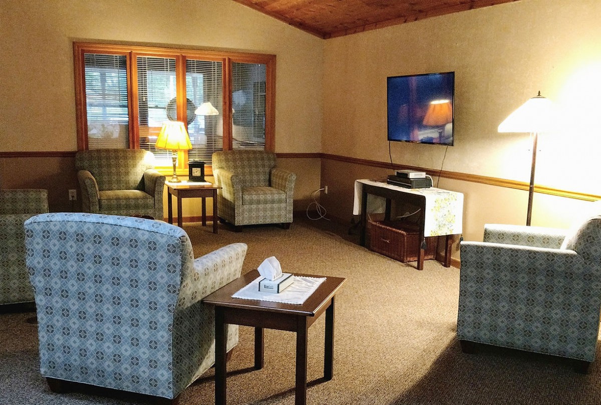 A cozy living room with plaid armchairs, a television, and warm lighting.