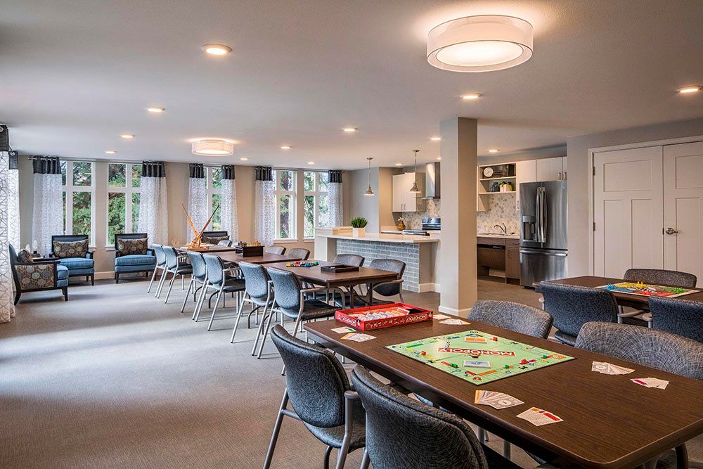A modern dining area with multiple tables and chairs, adjacent to a kitchen.
