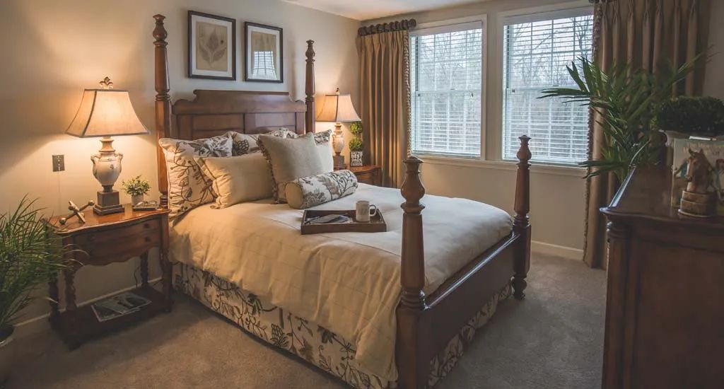 A cozy and well-decorated traditional bedroom with a wooden bed frame and soft lighting.