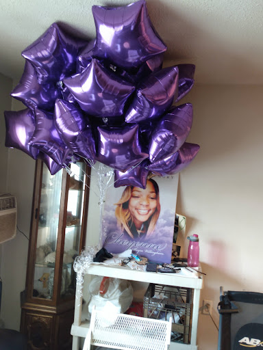 A vibrant display of purple balloons above a table featuring a poster.