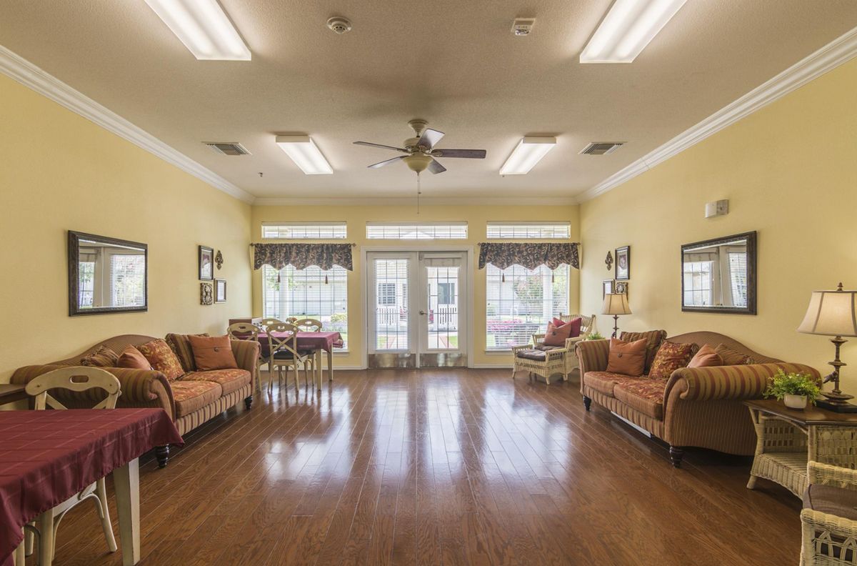 A spacious living room with comfortable couches, wooden flooring, and large windows letting in natural light.