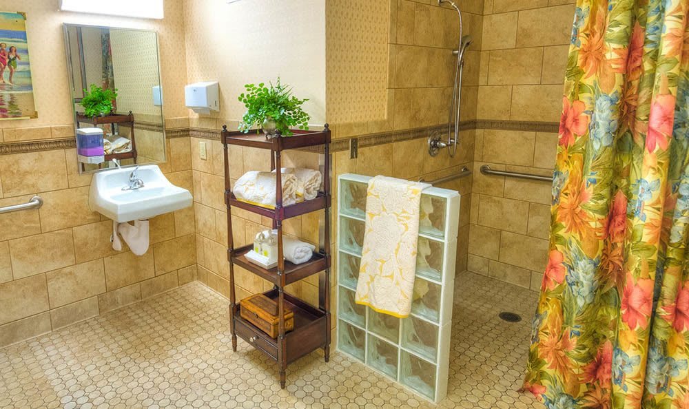 A bathroom with organized shelves holding towels and a small plant, featuring tiled walls and floor.