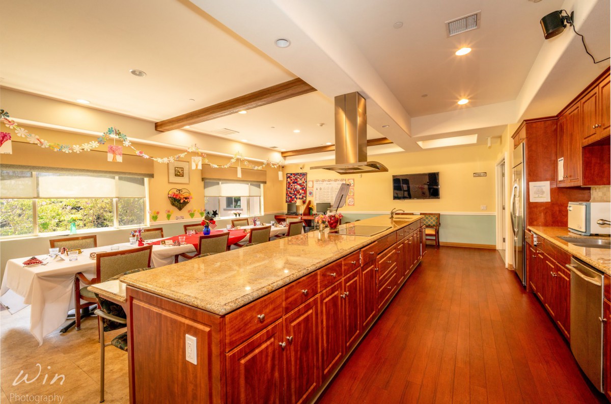 A spacious and modern kitchen with a large island, stainless steel appliances, and warm wood flooring.