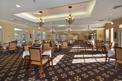 A spacious dining room with elegant chandeliers and neatly arranged tables and chairs.