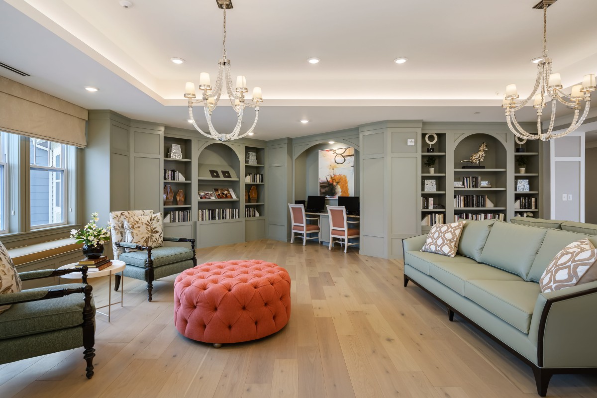 A spacious living room with elegant decor, featuring built-in bookshelves, a chandelier, and comfortable seating.