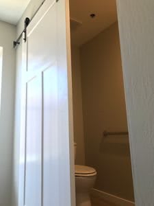 A bathroom partially visible behind a sliding barn door.