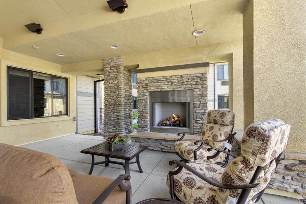 A cozy outdoor patio with a stone fireplace and comfortable seating.