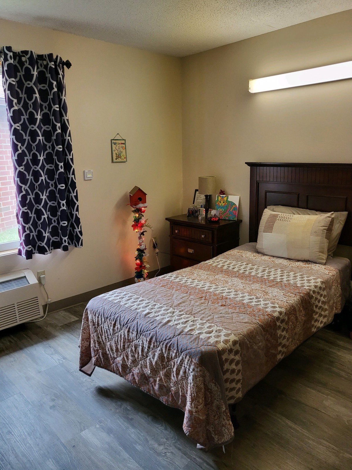 A cozy bedroom with a single bed, patterned curtains, and a small dresser.