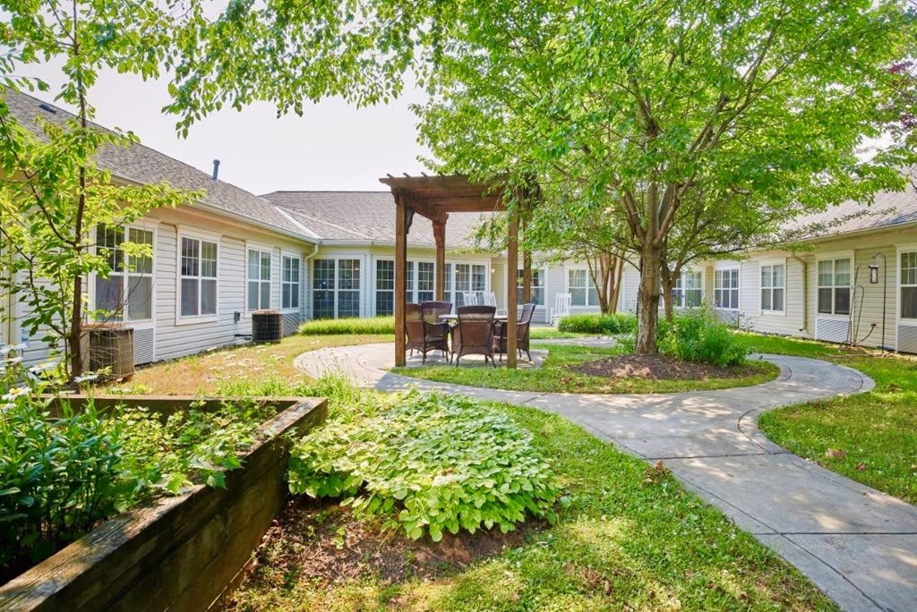 A serene courtyard with a pergola surrounded by greenery and pathways.