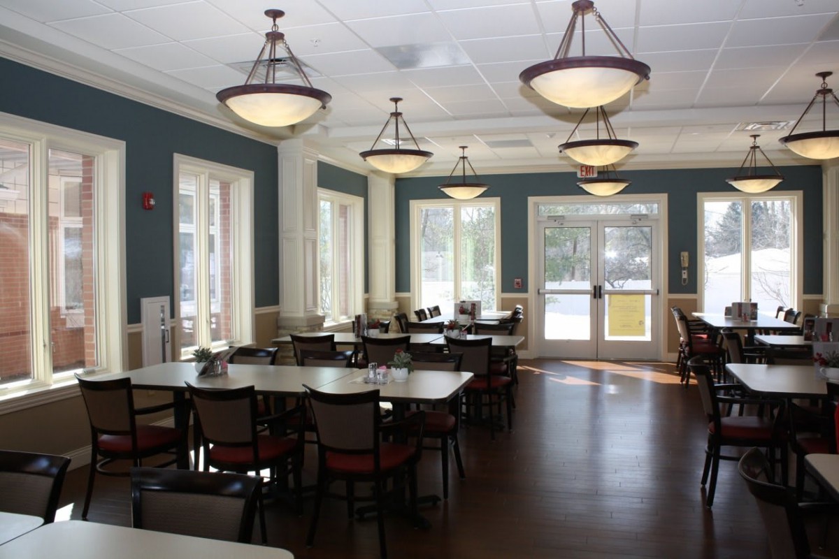 An empty dining area with neatly arranged tables and chairs under elegant lighting.