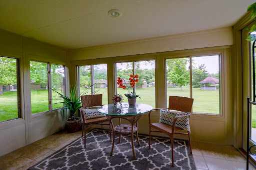 A cozy sunroom featuring a glass table and seating, surrounded by large windows that let in plenty of natural light.