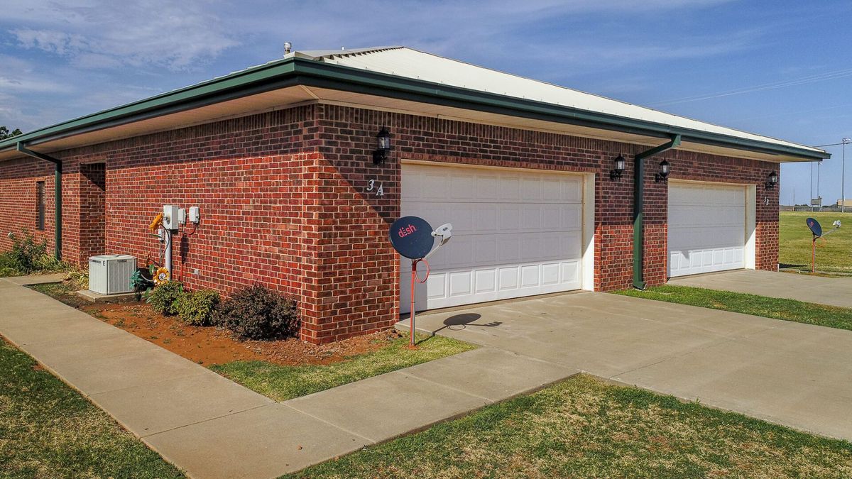 A brick house with a garage and satellite dish.