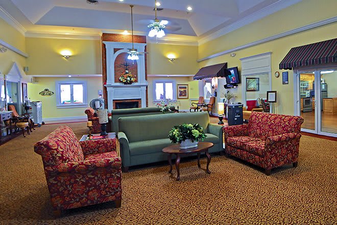A cozy living room with a central seating area, featuring a sofa, armchairs, and a coffee table, complemented by a warm fireplace.