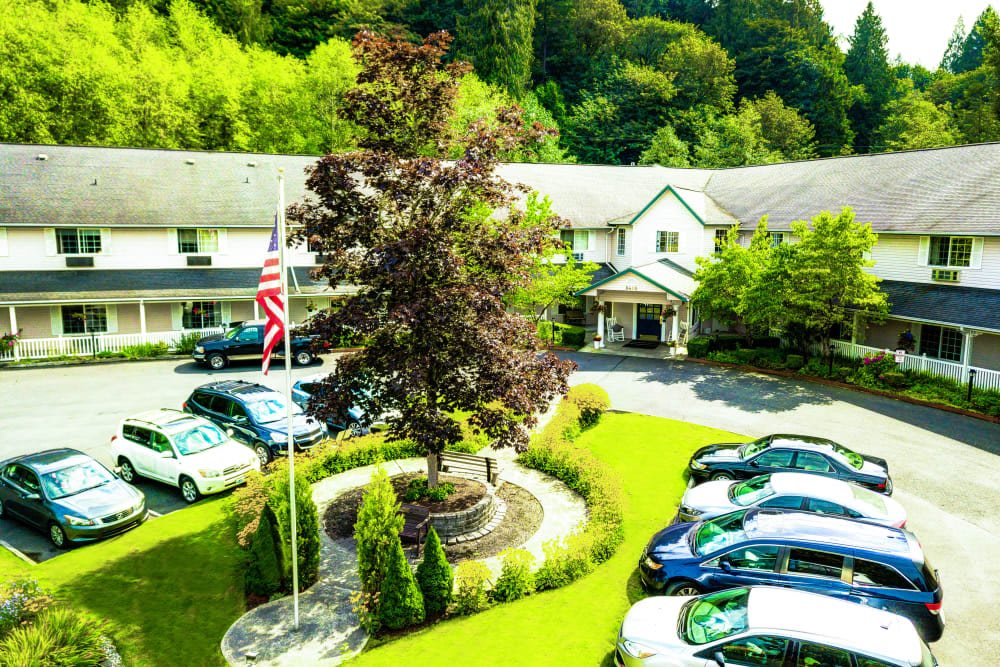 A scenic view of a building with well-maintained landscaping, surrounded by parked cars and lush greenery.