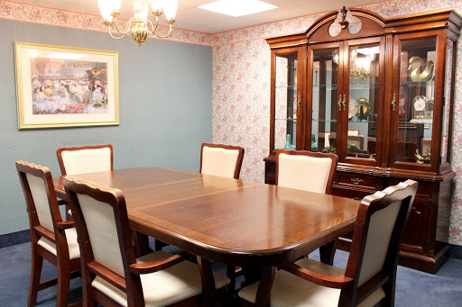 A cozy dining room featuring a large wooden table surrounded by upholstered chairs, complemented by elegant lighting and tasteful wall decor.