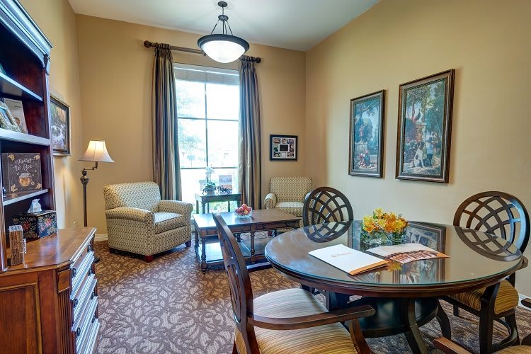 A cozy living room with chairs, a table, and artwork on the walls.
