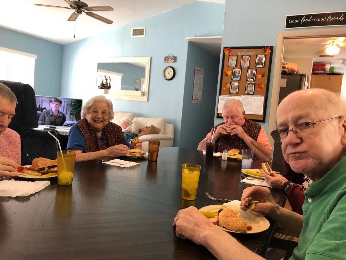 A group of elderly individuals enjoying a meal together around a dining table.