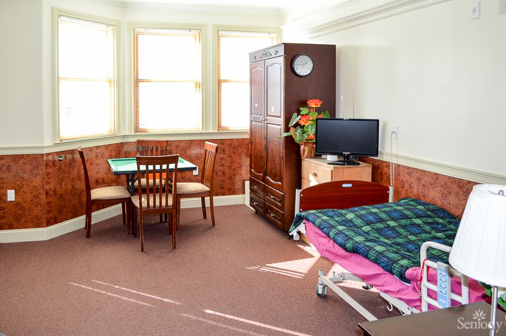 A cozy room with a bed, a small dining table, and a television.
