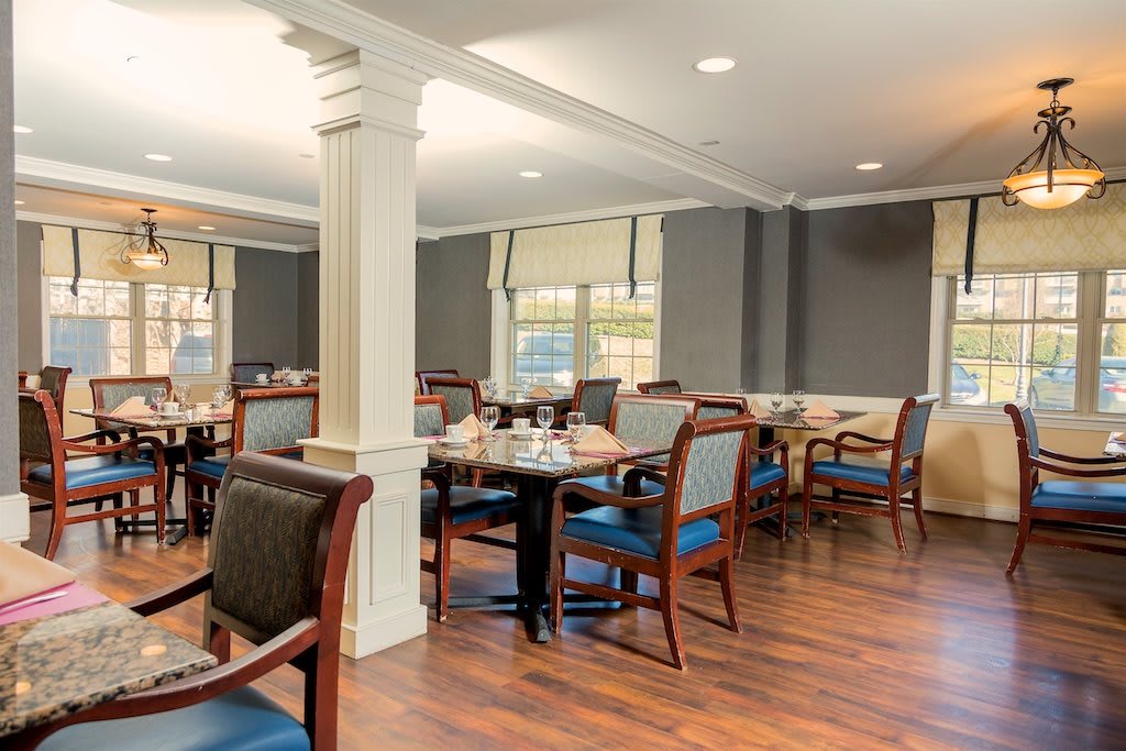 A spacious dining room with neatly arranged tables and chairs on a hardwood floor.
