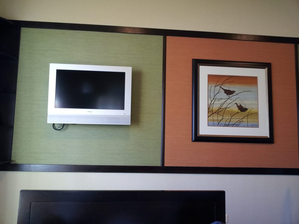 A small television and a framed artwork mounted on a color-blocked wall.