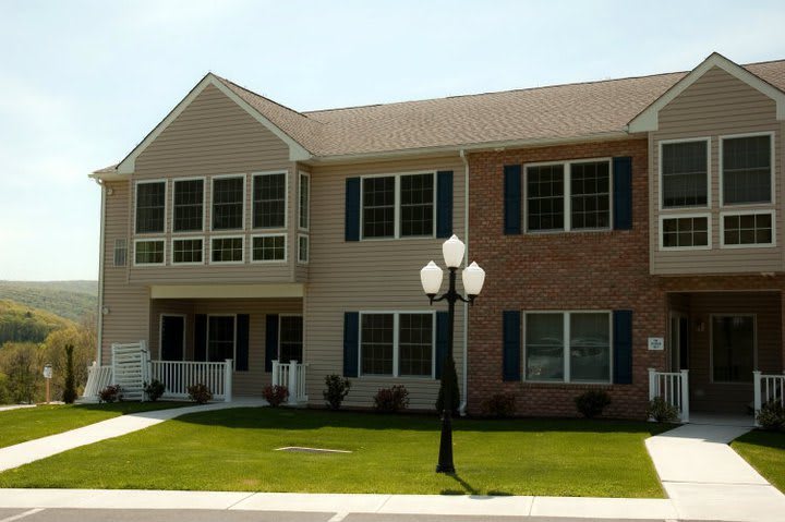 A suburban duplex with a brick facade and a well-maintained lawn.