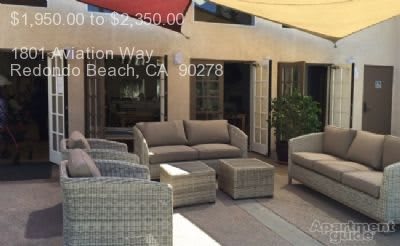 A cozy outdoor patio setup with cushioned seating and an umbrella, perfect for relaxing.