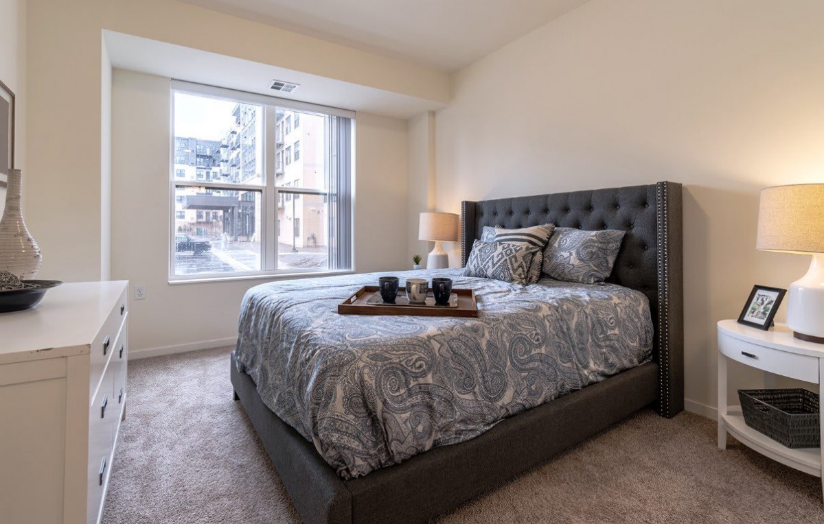 A modern bedroom with a large bed and a window allowing natural light to fill the space.