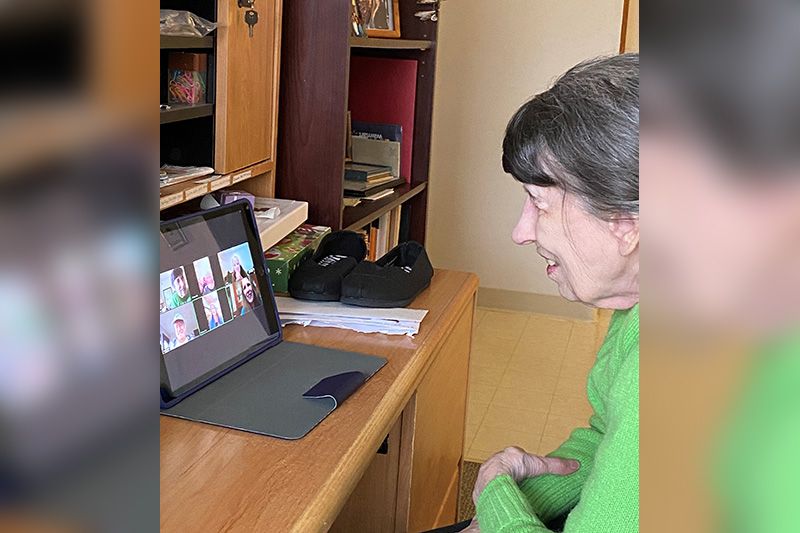 An elderly person engaged in a video call using a tablet indoors.