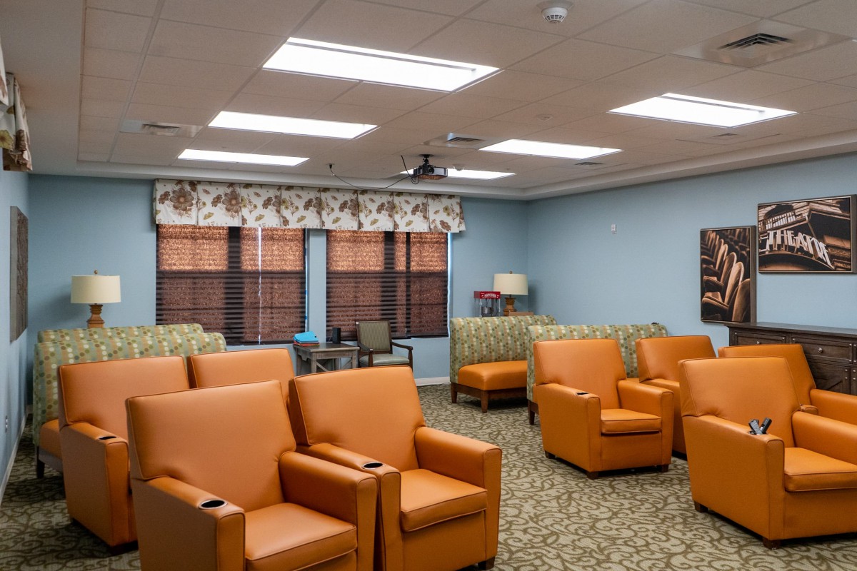 A comfortable waiting room with orange chairs, floral curtains, and soft lighting.