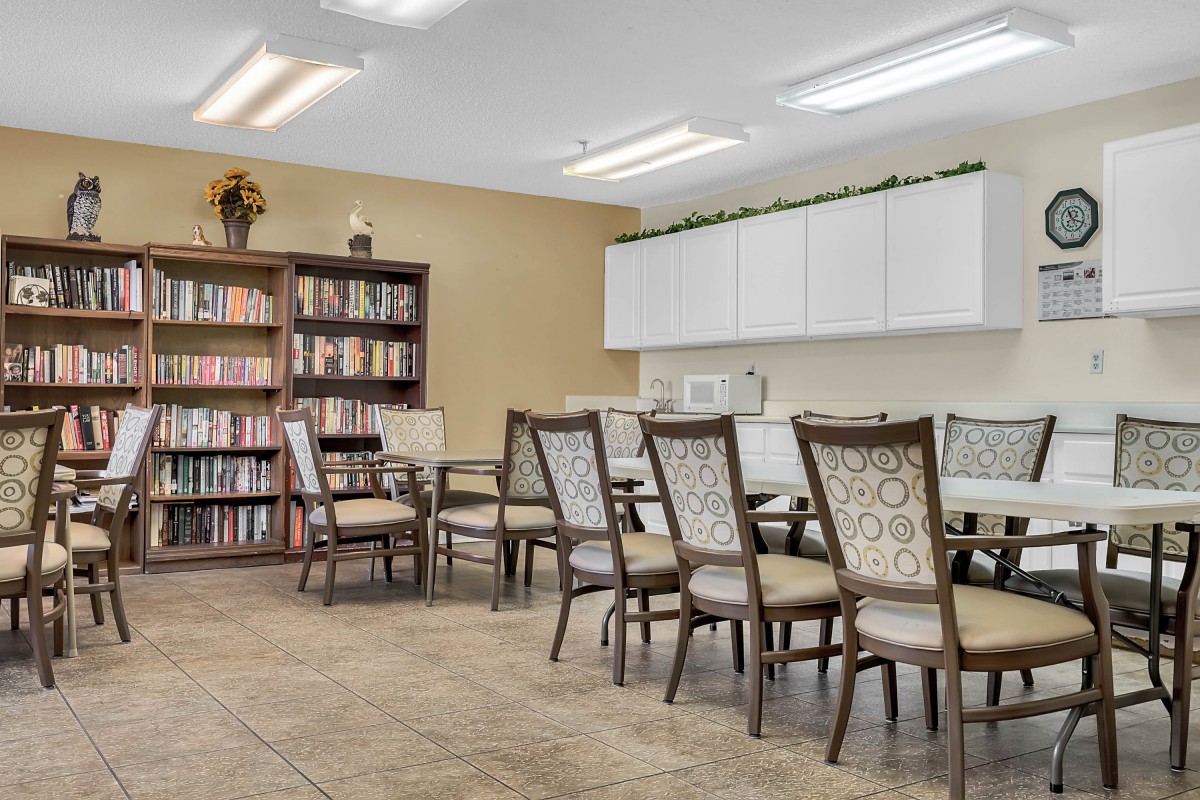 A well-organized meeting room with a large table, several chairs, and a bookshelf filled with books.
