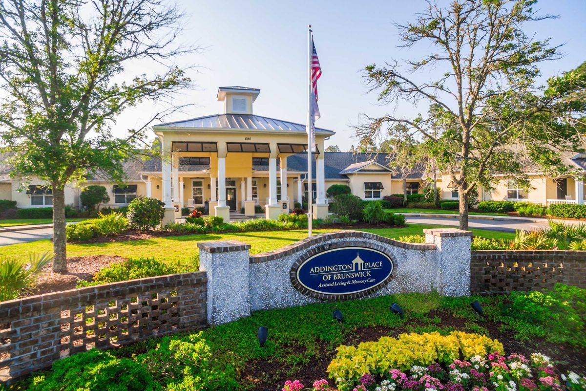 A beautiful building with a grand entrance surrounded by well-maintained gardens and flags.