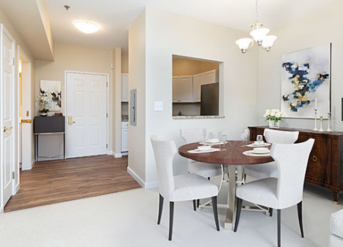 Modern dining area with a round table, elegant chairs, and an open kitchen in the background.
