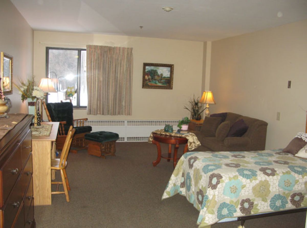 A cozy living space with a bed, sofa, and desk near a window.