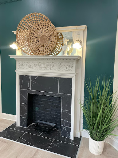 A beautifully styled modern fireplace with a striking green wall backdrop, featuring decorative elements and a touch of greenery.