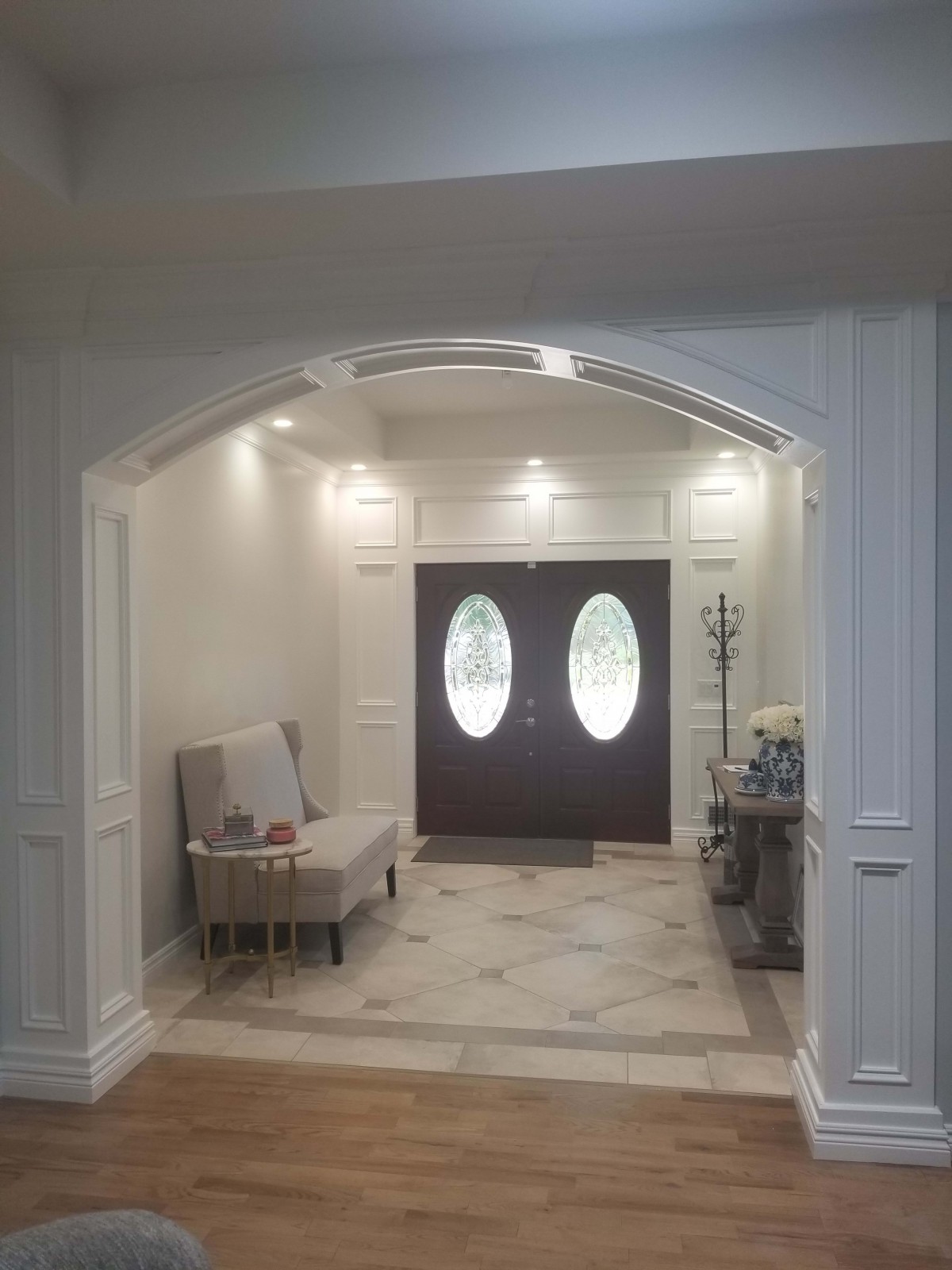 A cozy foyer featuring elegant double doors, a seating area, and soft lighting.