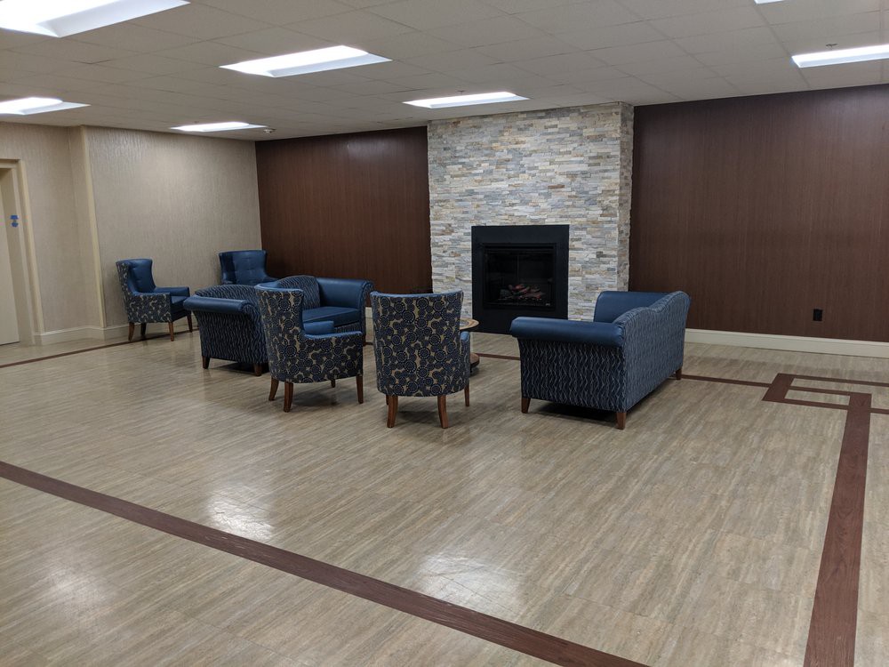 A modern lounge area with sofas and chairs arranged around a fireplace.