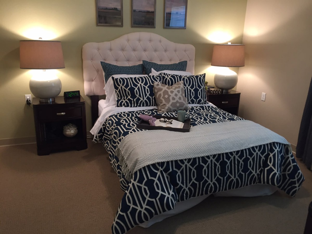 A cozy and stylishly decorated bedroom with patterned bedding, soft pillows, and warm lighting.