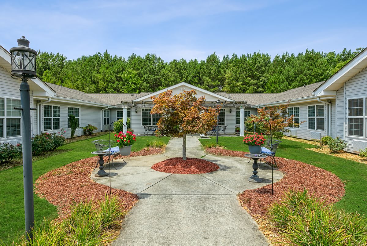 A charming building with a landscaped courtyard featuring a central tree, surrounded by benches and pathways.