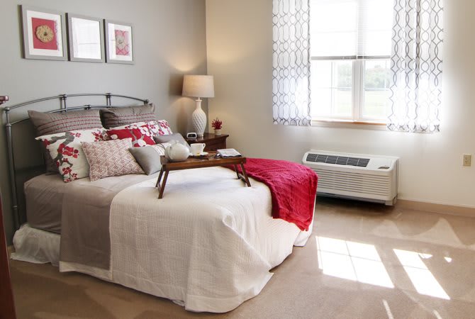 A cozy and stylish bedroom with a neatly made bed, soft lighting, and natural light streaming in through the window.