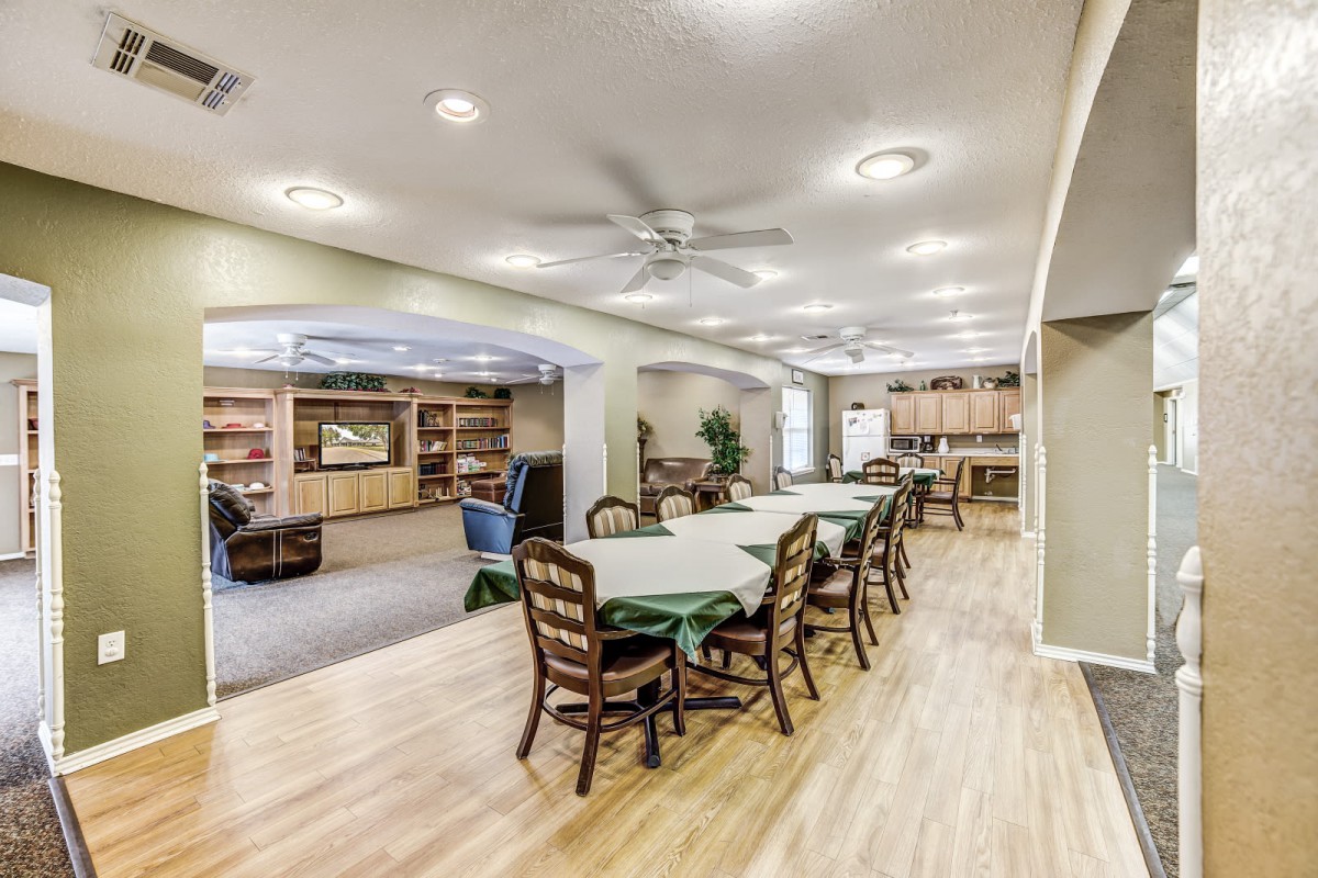 A spacious interior with a dining area connected to a kitchen, featuring wooden floors and modern furnishings.