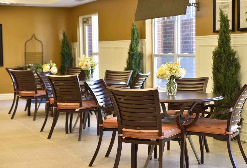 An elegant dining area featuring neatly arranged tables and chairs, decorated with vases of flowers.