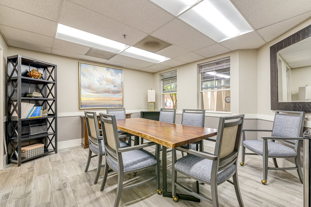 A modern conference room with a wooden table and chairs, adorned with artwork and natural lighting.