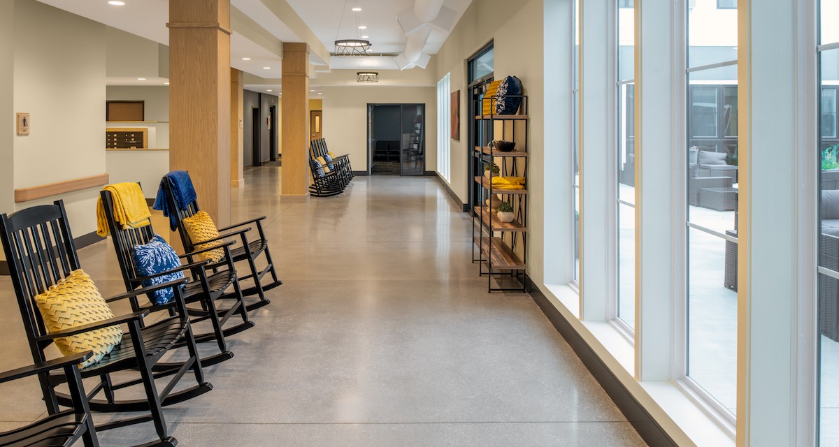 A modern hallway with rocking chairs and large windows.