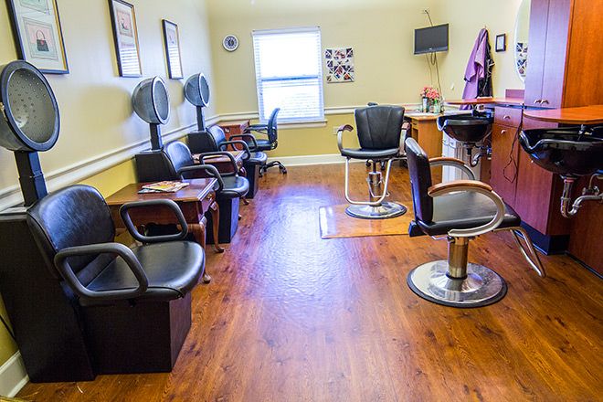 Interior view of a hair salon with multiple chairs and hair dryers.