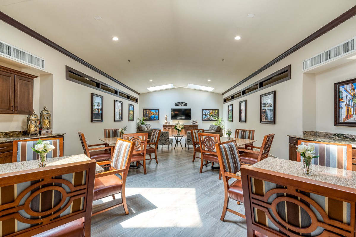 A well-lit dining area with wooden tables and chairs, featuring modern decor and framed pictures on the walls.
