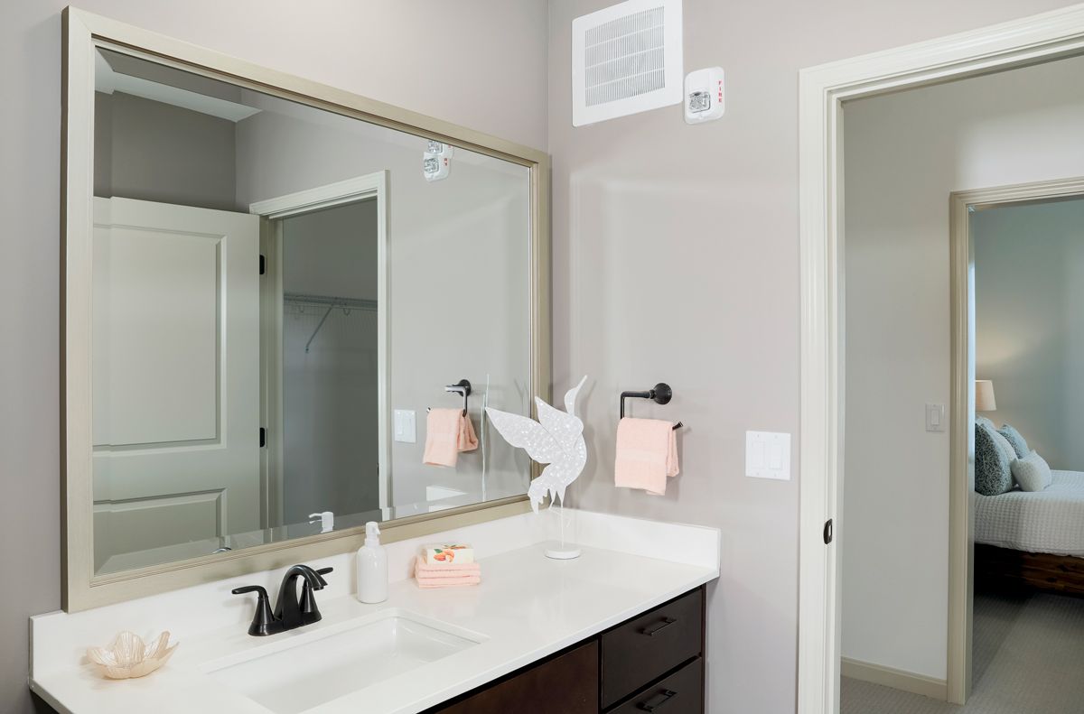A modern bathroom with a large mirror, sink, and decorative elements.