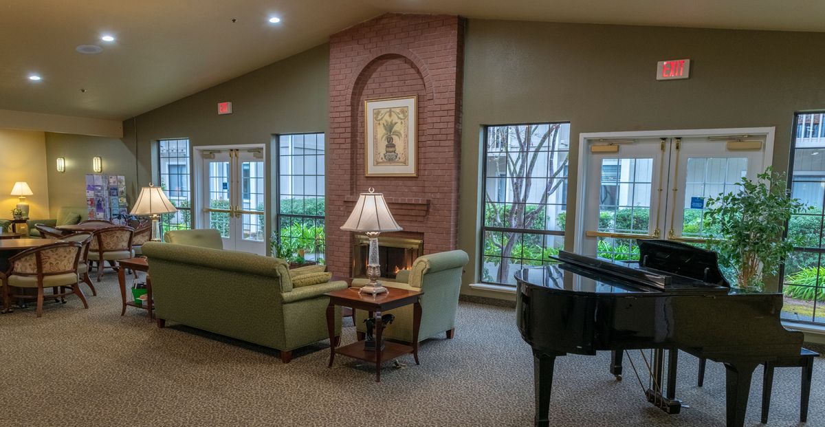 A cozy living room with a piano, sofas, and a fireplace.