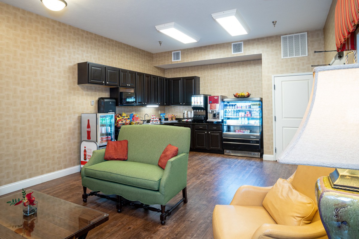 A modern lounge area with a kitchenette, featuring comfortable seating and well-equipped appliances.